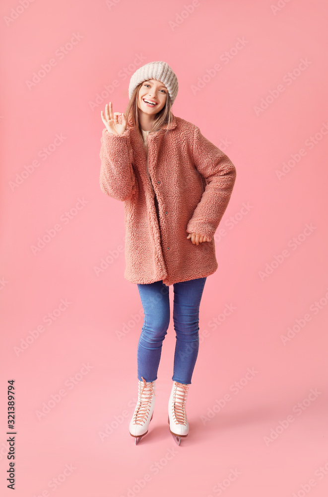 Beautiful young woman on ice skates against color background