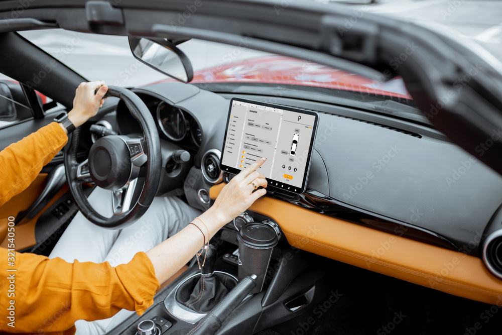 Cheerful woman controlling car with a digital dashboard, switching autopilot mode while driving a ca