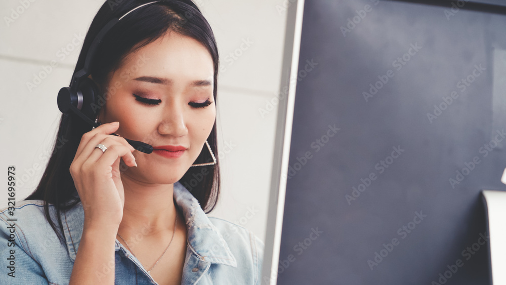 Customer support agent or call center with headset works on desktop computer while supporting the cu