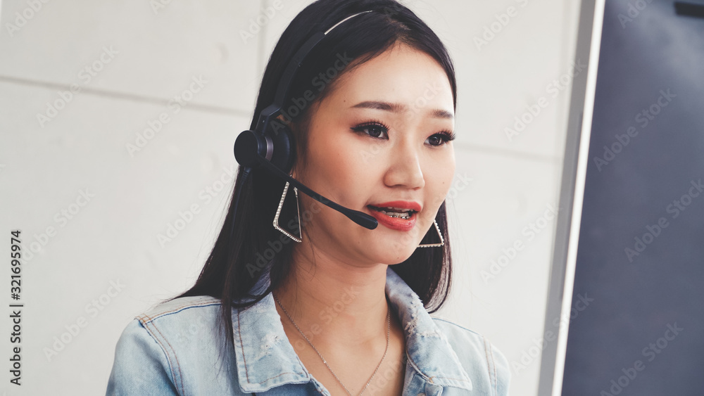 Customer support agent or call center with headset works on desktop computer while supporting the cu