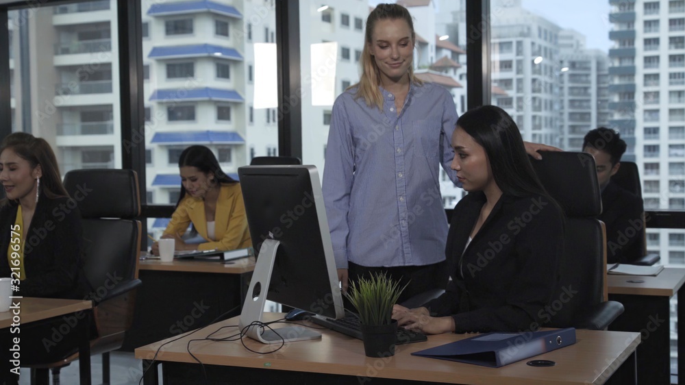 Young leader gives advice to young woman worker in modern office. Leadership and training concept.