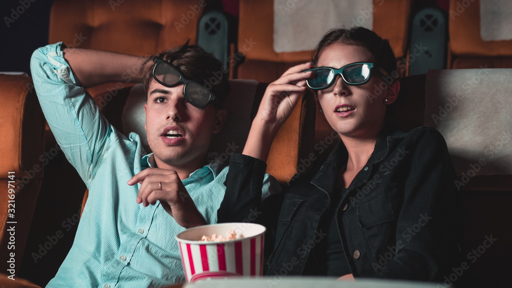 Man and woman in the cinema watching a movie with 3D glasses. with interest looking at the screen, e