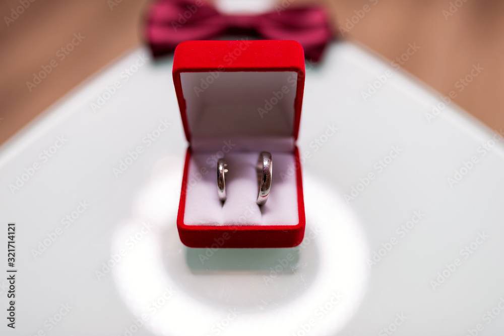 Red box with two golden wedding rings on blurred background, big day concept. Marriage, wedding.