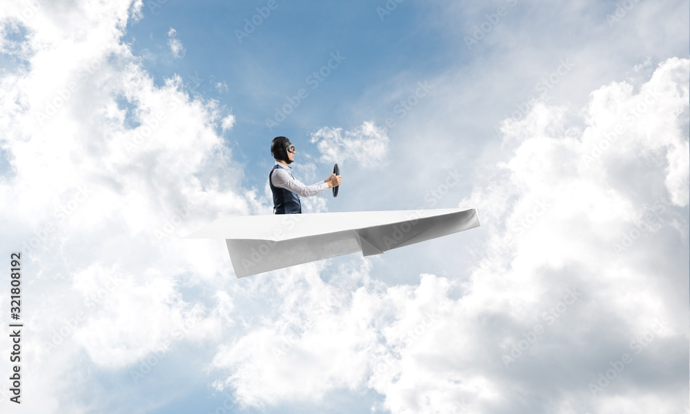 Businessman in aviator hat sitting in paper plane