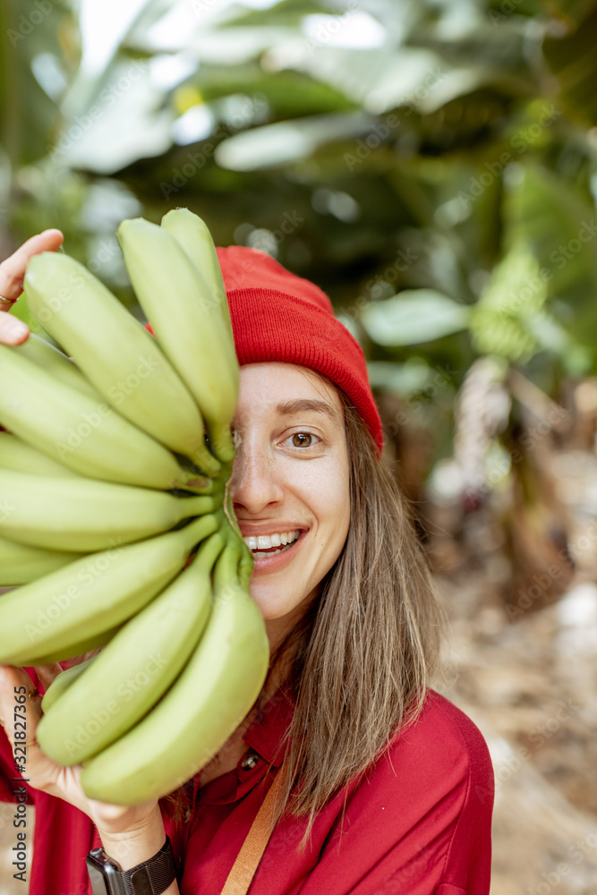 Facial portrait of a cute woman holding a stem with fresh green bananas in front of her face. Health