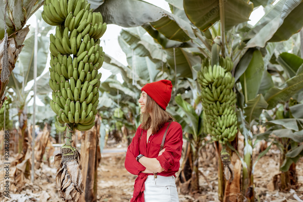 Portrait of a happy woman as a farmer or tourist dressed in red shirt and hat standing on the planta