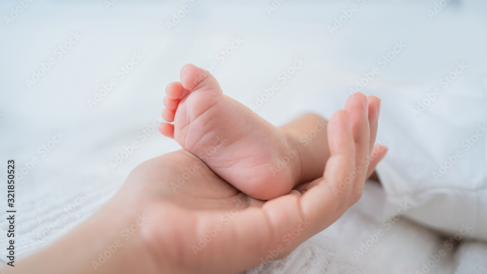 The mothers hand touches the babys foot.