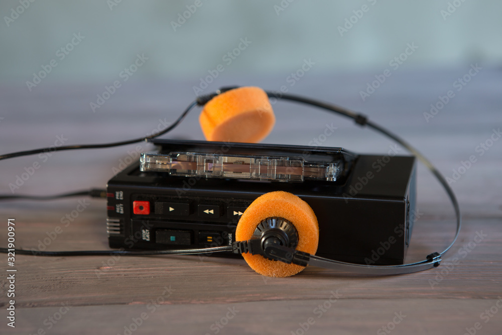 Old portable cassette player and headphones on a wooden background