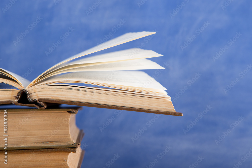 Education and reading concept - group of books on the wooden table, blue blackboard background. Teac