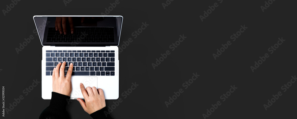 Person using a laptop computer on a solid color background