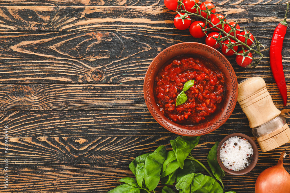 Bowl with tomato sauce and ingredients on table