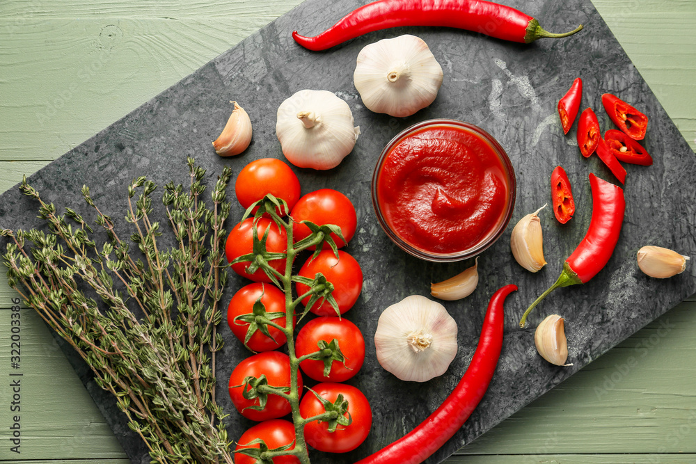 Bowl with tomato sauce and ingredients on table