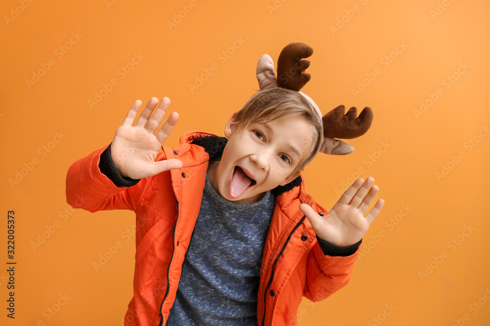 Funny little boy with deer horns on color background