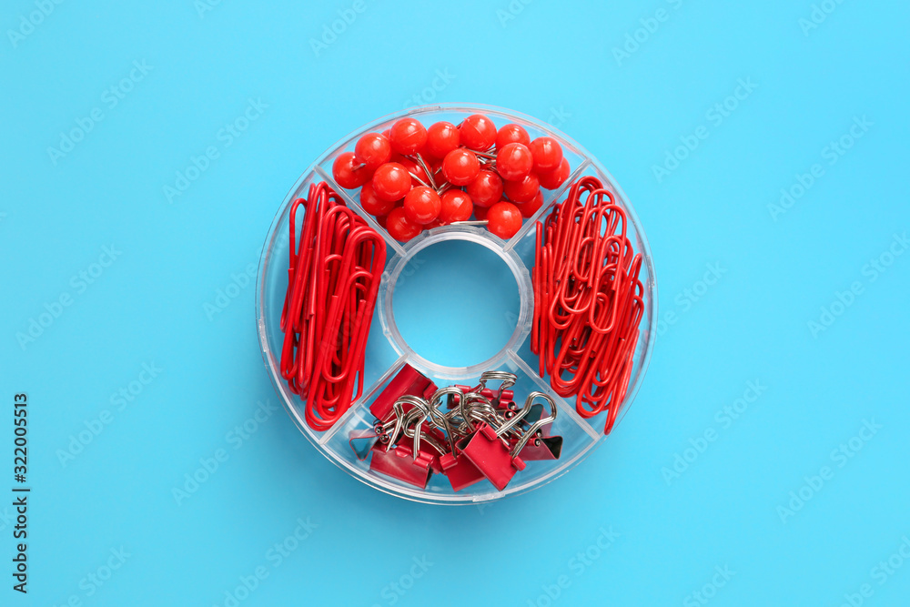 Box with clips and pins on color background