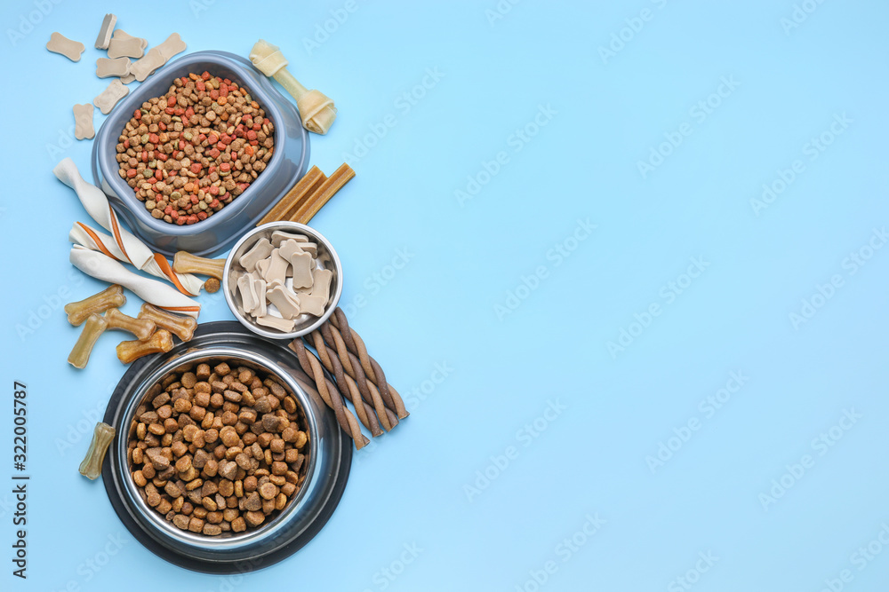 Bowls with dry pet food on color background