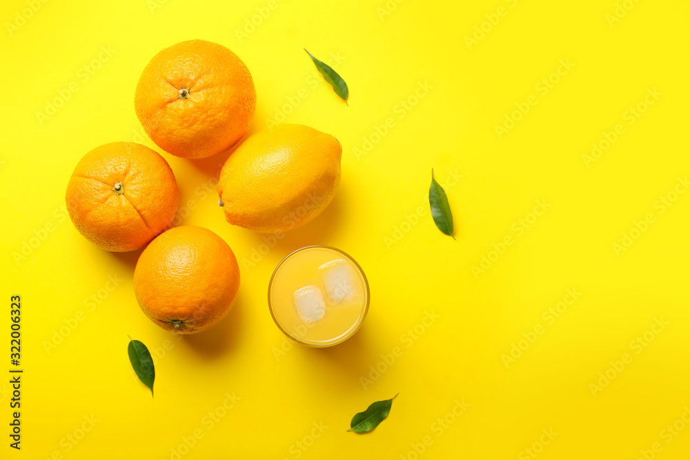 Glass of fresh orange juice and fruit on color background