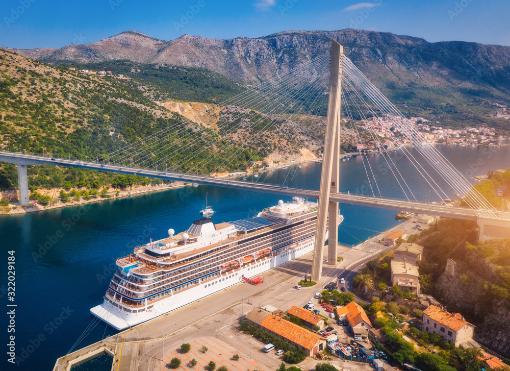 Aerial view of cruise ship under beautiful bridge at sunset. Port in Dubrovnik, Croatia. Summer land