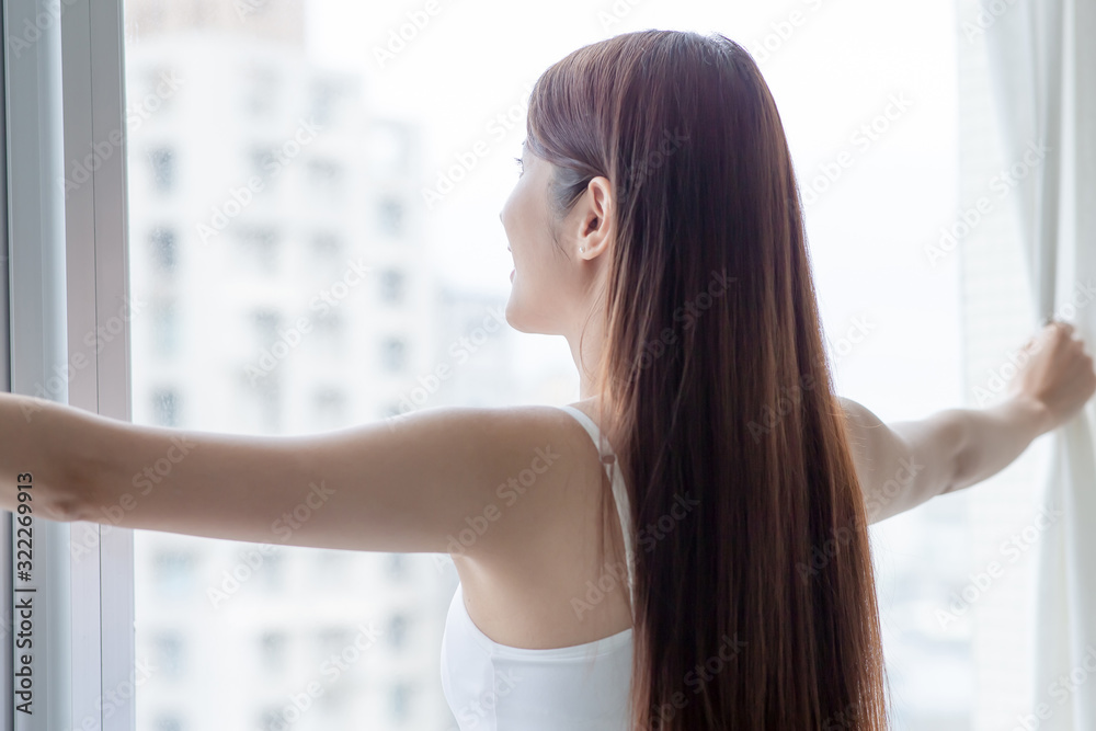 asian woman opening curtain