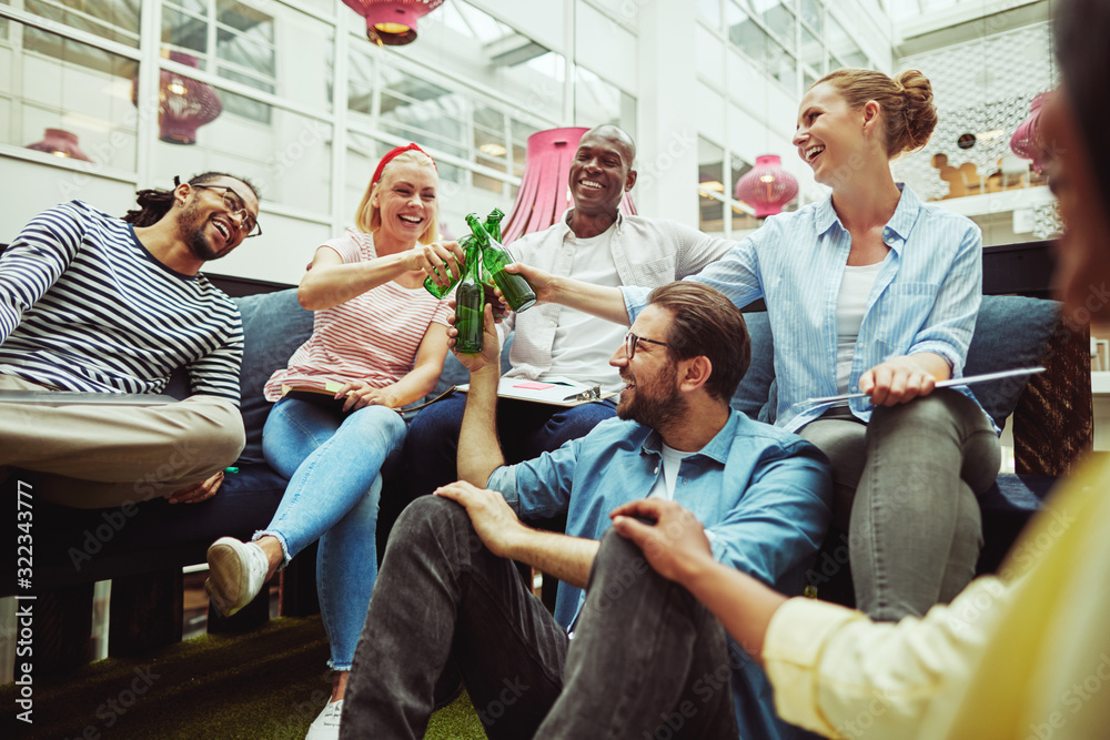 Diverse group of laughing businesspeople toasting with beers aft