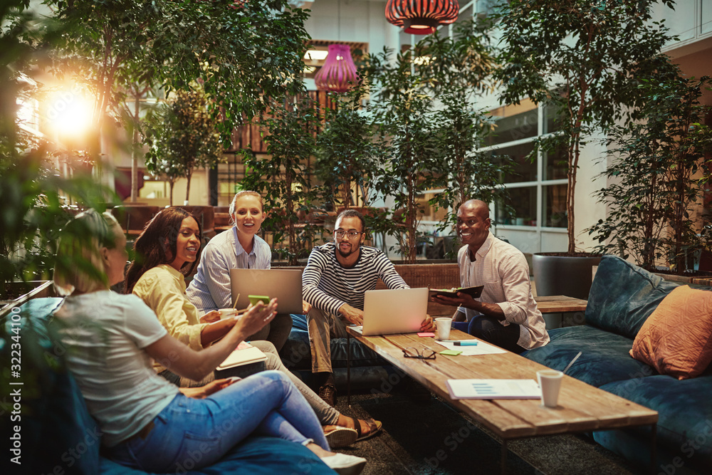 Businesswoman showing smiling diverse colleagues something on he