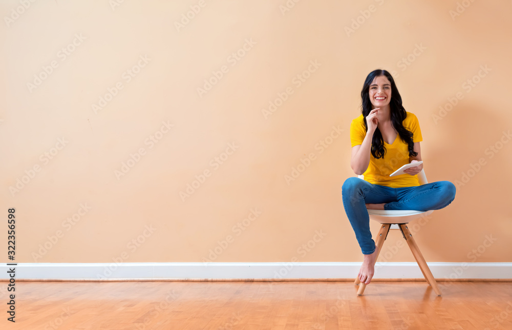 Young woman using her tablet sitting in a chair