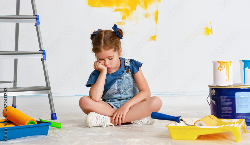 Repair in apartment. Tired child girl paints wall .