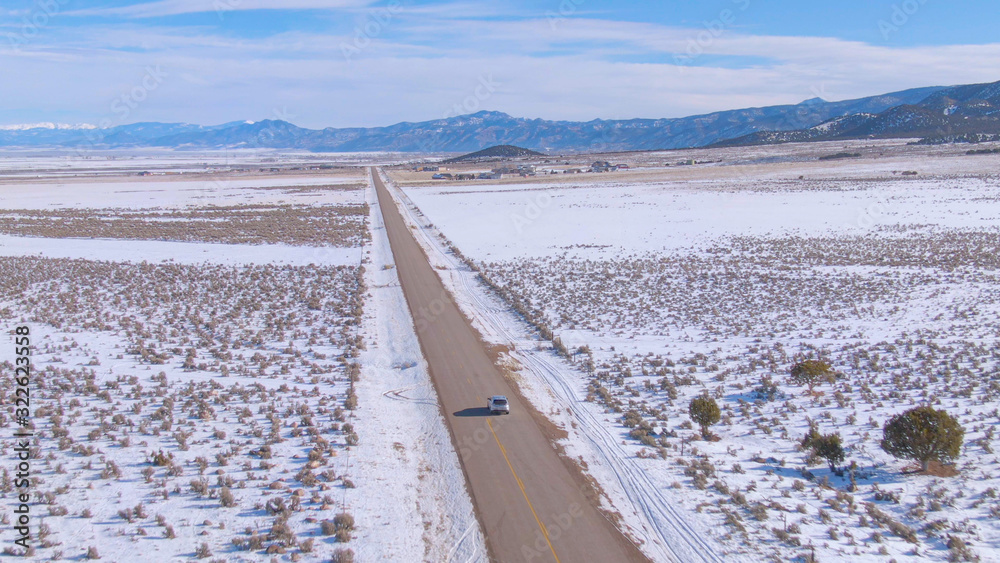 空中：风景优美的柏油公路引领银色SUV穿越雪域。