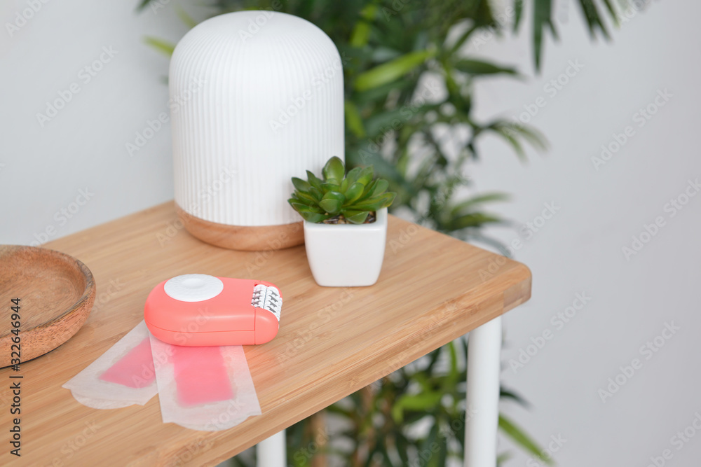 Modern epilator with wax strips on table in bathroom