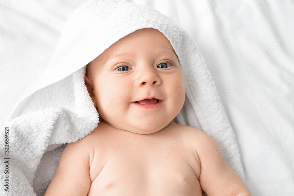 Portrait of cute little baby with towel lying on bed