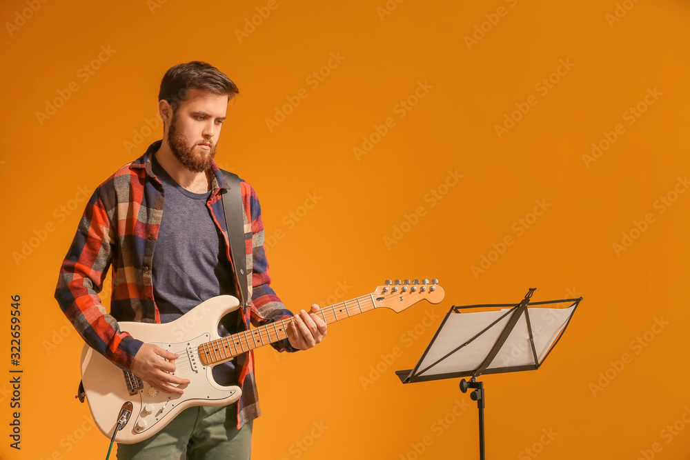 Young man playing guitar on color background