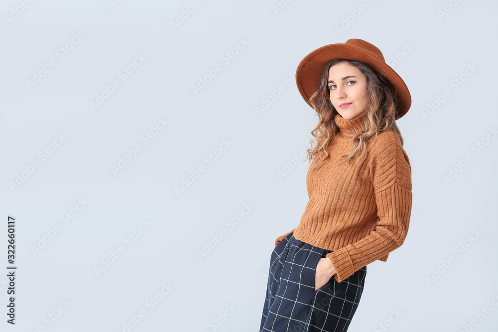 Beautiful young woman in warm sweater on light background