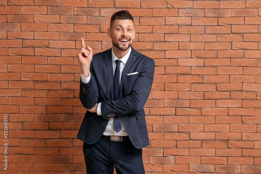 Businessman with raised index finger on brick background. Concept of choice