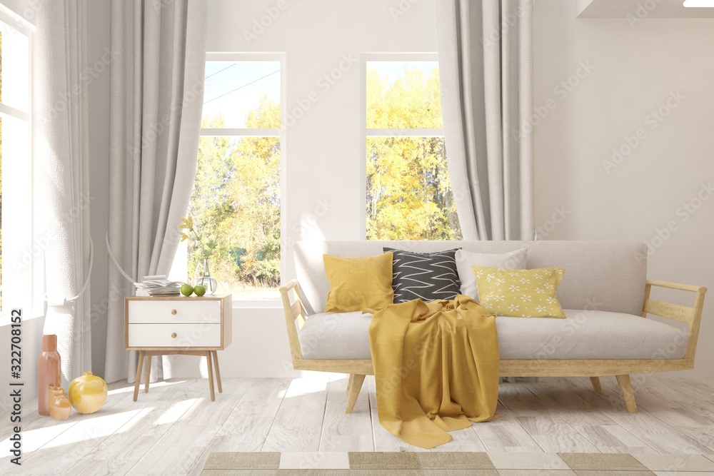 Stylish room in white color with sofa and autumn landscape in window. Scandinavian interior design. 