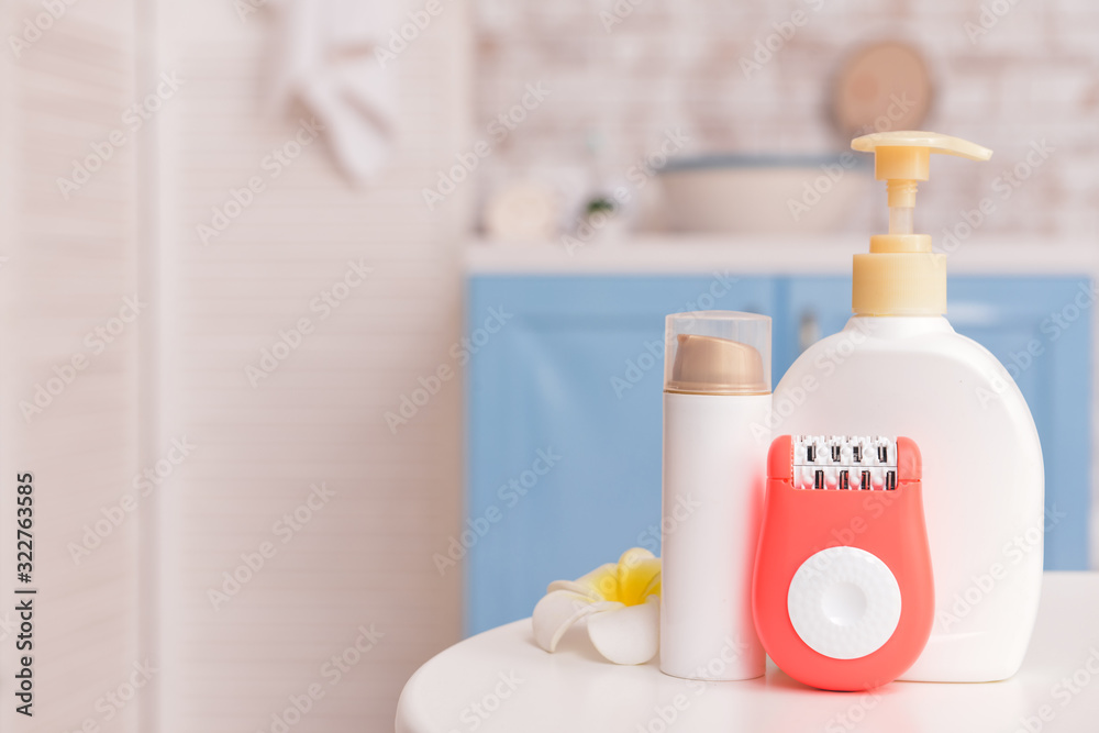 Modern epilator with cosmetics on table in bathroom