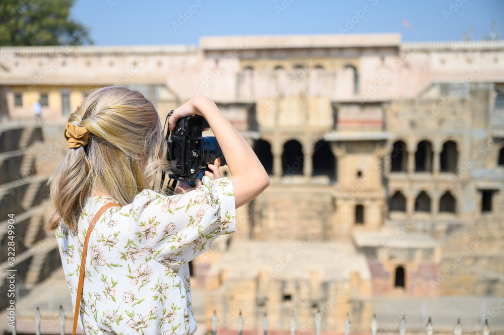 Young woman capture photo of Chand Baori Stepwell in the village of Abhaneri, Rajasthan, India