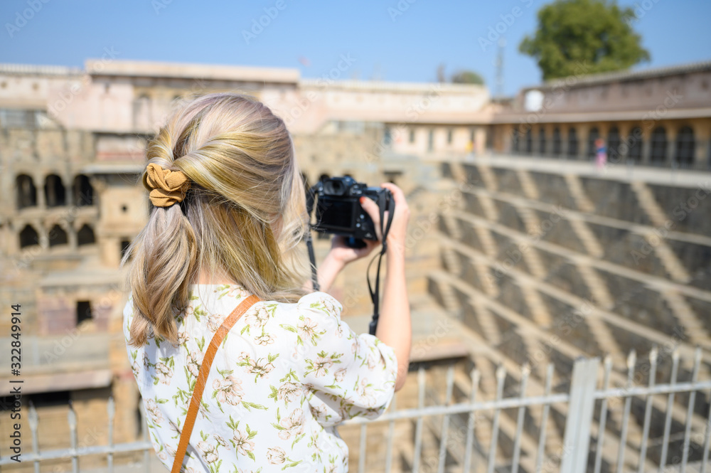 Young woman capture photo of Chand Baori Stepwell in the village of Abhaneri, Rajasthan, India