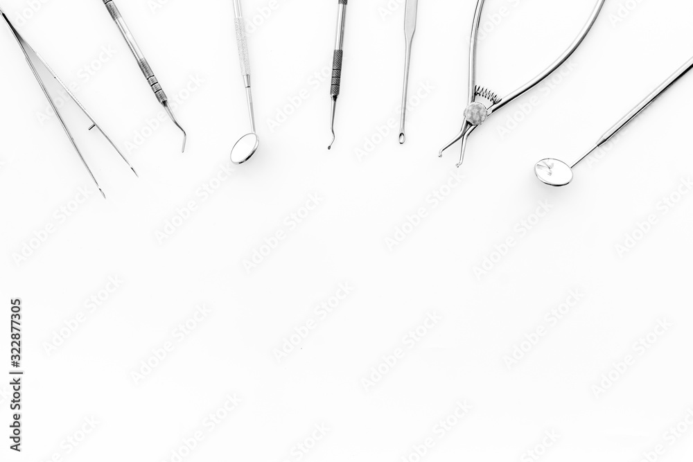 Stomatological tools on dentists desk on white background top-down pattern frame copy space