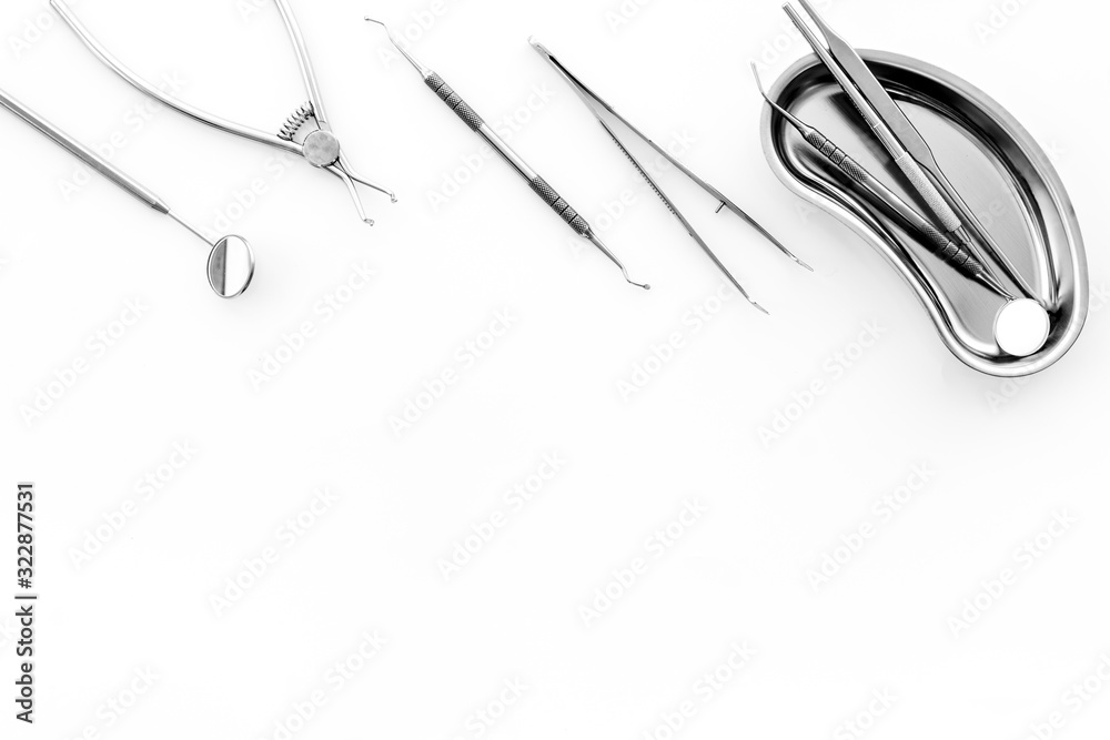 Stomatological tools in tray on dentists desk on white background top-down frame copy space