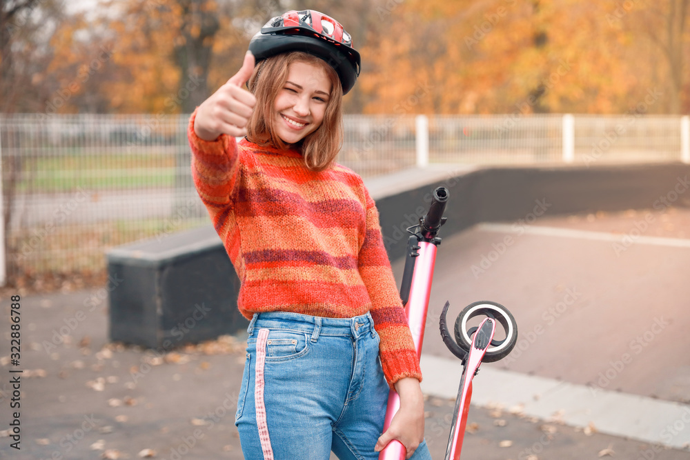 青少年女孩在滑冰公园里用脚踢滑板车竖起大拇指