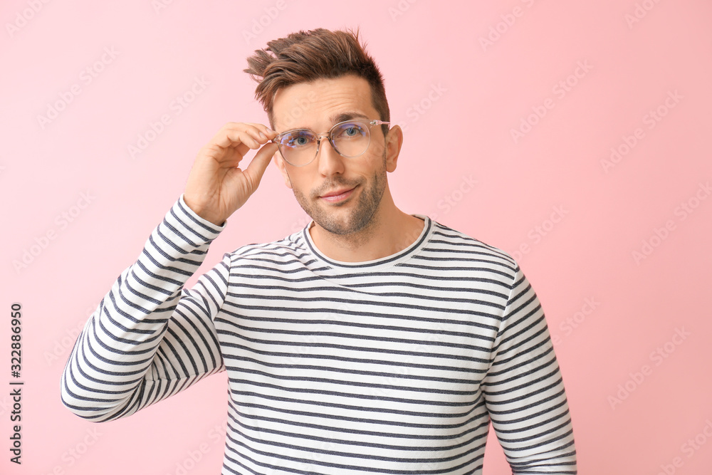 Young man with stylish eyeglasses on color background