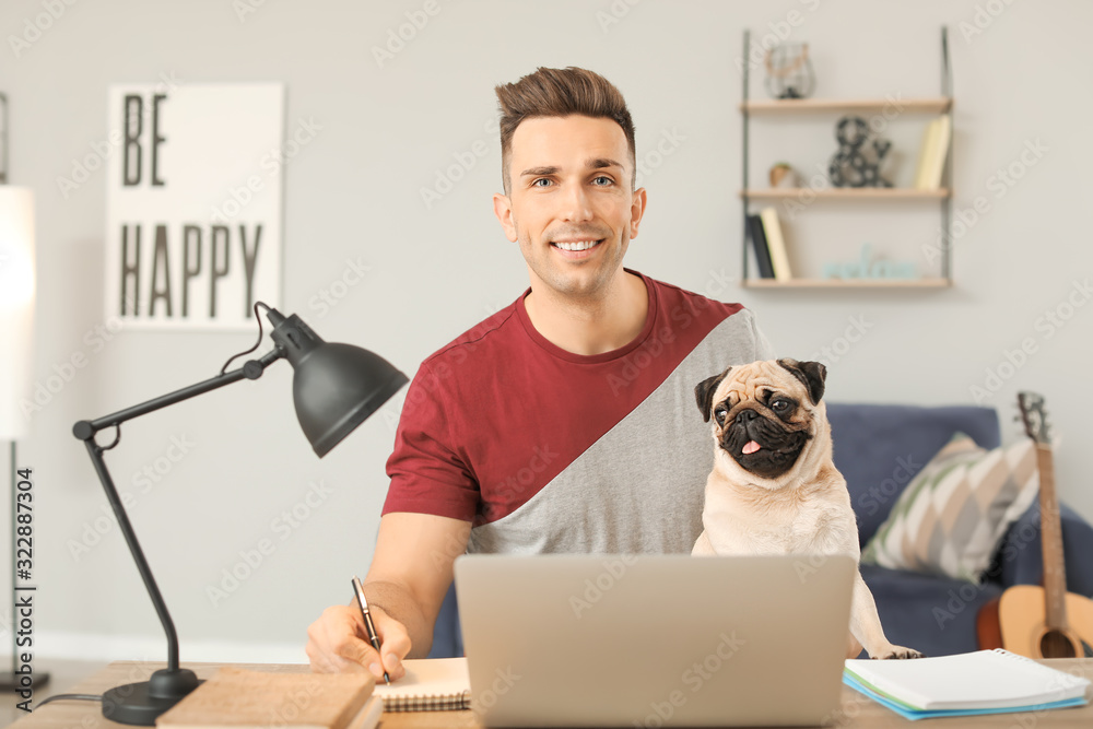 Handsome man with cute pug dog and laptop at home