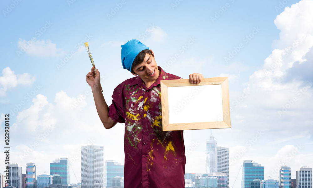 Young handsome painter artist holding paintbrush