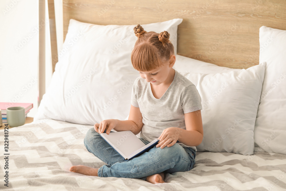 Cute little girl reading book at home