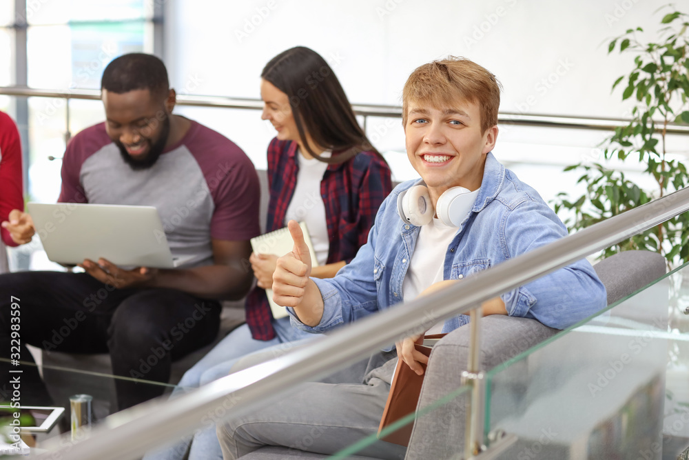 Male student showing thumb-up gesture in library