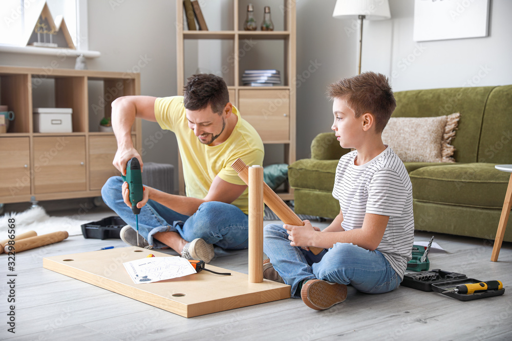 Father and his little son assembling furniture at home