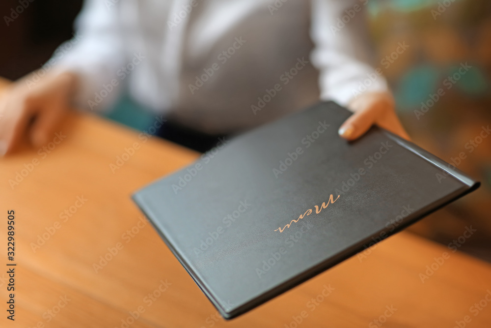 Young woman with menu sitting in restaurant, closeup