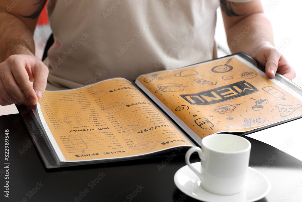 Young man with menu sitting in restaurant