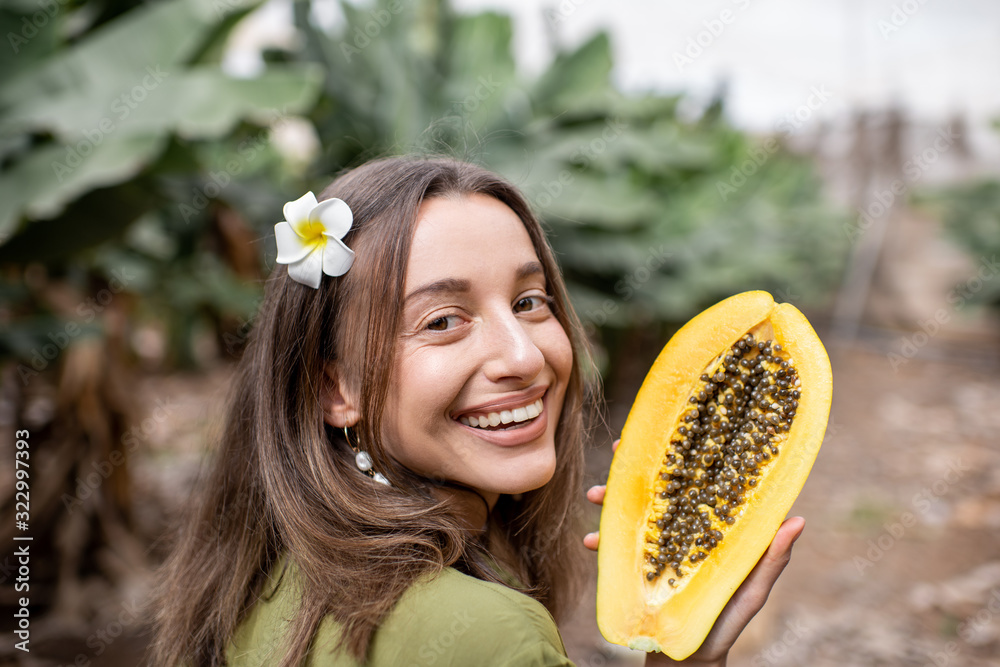 种植园里一个年轻女人拿着木瓜切片的肖像。素食主义的概念，治愈