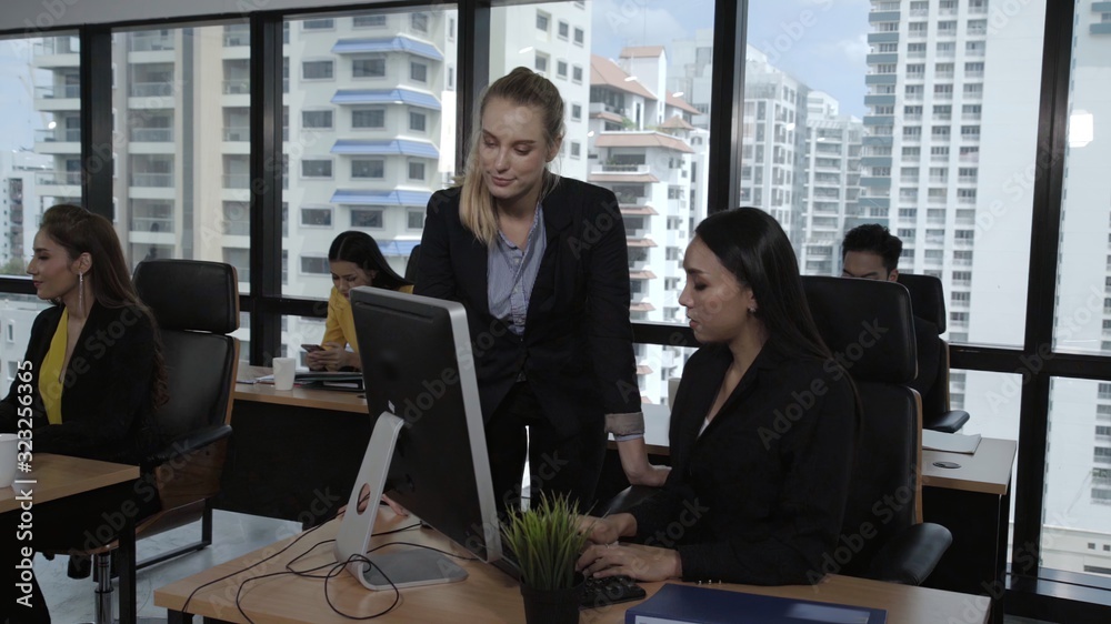 Young leader gives advice to young woman worker in modern office. Leadership and training concept.