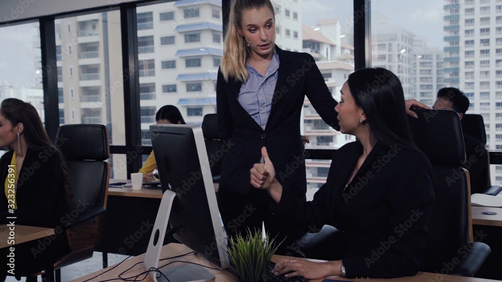 Young leader gives advice to young woman worker in modern office. Leadership and training concept.